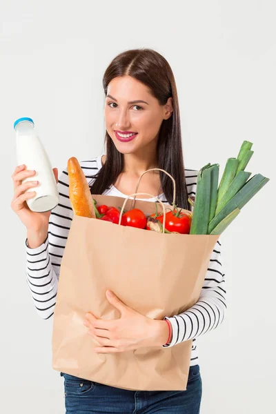 Retrato de una hermosa mujer sonriente sosteniendo una bolsa de papel con comida fresca orgánica aislada sobre fondo blanco . —  Fotos de Stock