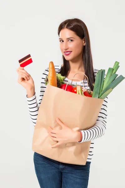 Портрет красивой улыбающейся женщины, держащей в руках бумажный пакет с органическими свежими продуктами на белом фоне . — стоковое фото