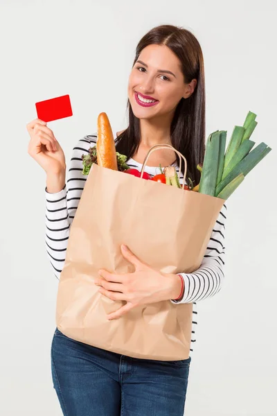 Retrato de una hermosa mujer sonriente sosteniendo una bolsa de papel con comida fresca orgánica aislada sobre fondo blanco . —  Fotos de Stock