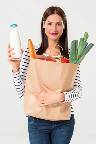 Retrato de una hermosa mujer sonriente sosteniendo una bolsa de papel con comida fresca orgánica aislada sobre fondo blanco . —  Fotos de Stock