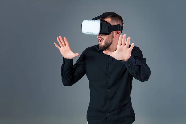 Συναισθηματική νεαρός χρησιμοποιώντας μια συσκευή VR και βιώνει εικονικής πραγματικότητας σε γκρίζο φόντο — Φωτογραφία Αρχείου