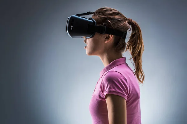 Wanita muda mengenakan headset realitas maya di studio. Emosi. Tampilan samping — Stok Foto