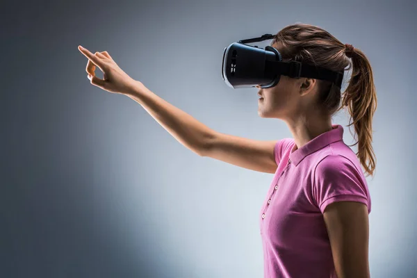 Young woman wearing virtual reality headset in studio. Emotions. Side view — Stock Photo, Image