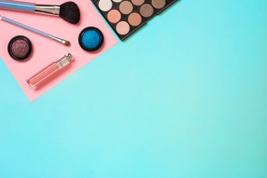 Çeşitli kozmetik ve mavi arka plan üzerinde fırçalar