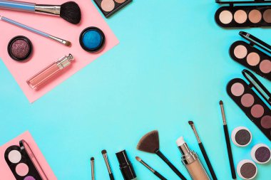 Çeşitli kozmetik ve mavi arka plan üzerinde fırçalar