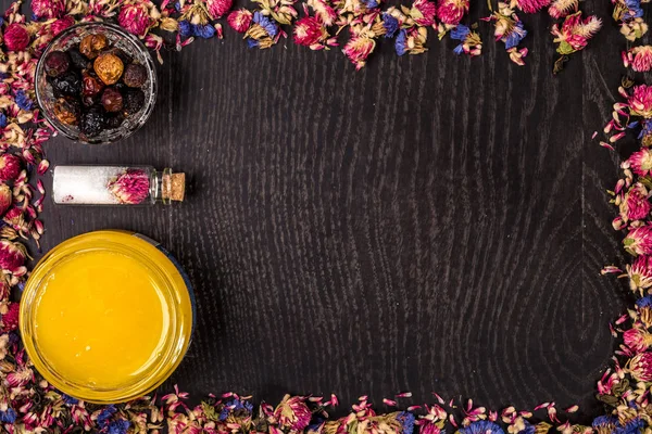 Organik bal ahşap arka plan üzerinde küçük bir kavanoz, çamur ve toprak toz içinde. Çerçeve kurutulmuş çiçek