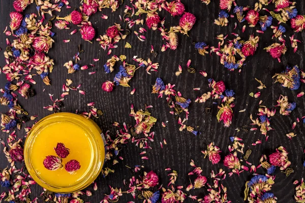 Organik bal ahşap arka plan üzerinde küçük bir kavanoza. Kuru çiçekler