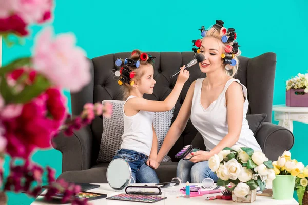 Mom and daughter in the studio on the sofa in the curlers make up and have fun
