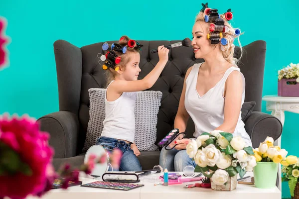 Anne ve kızı curlers içinde kanepede stüdyoda makyaj ve iyi eğlenceler