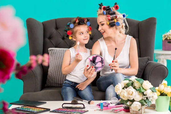 Anne ve kızı curlers içinde kanepede stüdyoda makyaj ve iyi eğlenceler