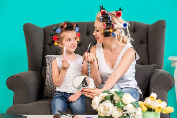 Мама и дочь в студии на диване в бигуди макияж и веселиться — стоковое фото