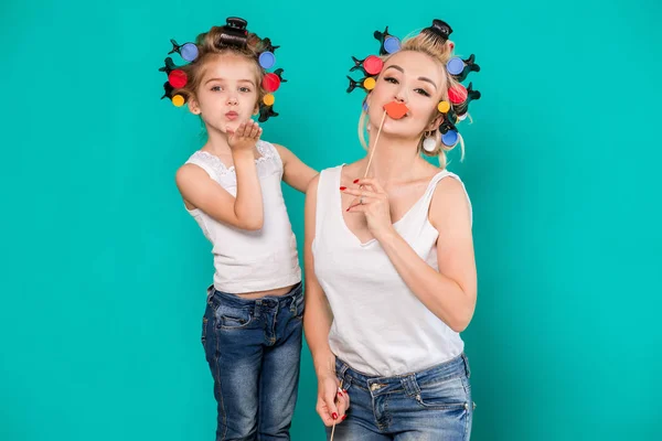 Família engraçada em um fundo de parede azul brilhante. Mãe e sua filha menina com um papel acessórios . — Fotografia de Stock