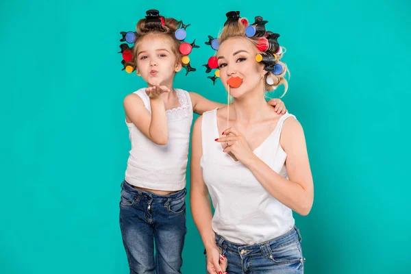 Família engraçada em um fundo de parede azul brilhante. Mãe e sua filha menina com um papel acessórios . — Fotografia de Stock