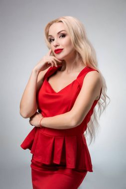 Gri arka plan üzerinde Kırmızı elbiseli çekici genç kadın