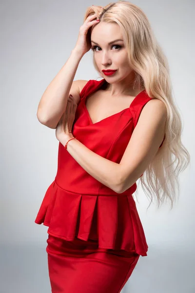 Γοητευτική νεαρή γυναίκα με κόκκινο φόρεμα σε γκρι φόντο — Φωτογραφία Αρχείου