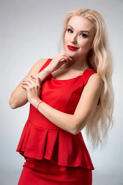Γοητευτική νεαρή γυναίκα με κόκκινο φόρεμα σε γκρι φόντο — Φωτογραφία Αρχείου