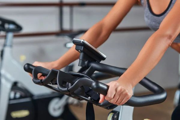 Frau übergibt an Stange stationäres Fahrrad im Fitnessstudio — Stockfoto