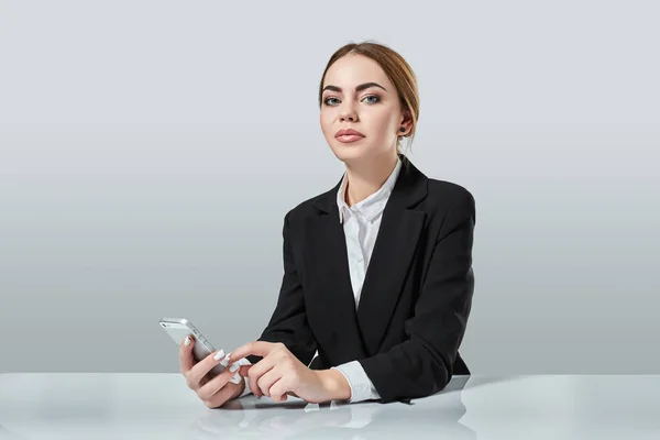 Atraente mulher de cabelos escuros vestida com um terno preto está sentado à mesa em um escritório . — Fotografia de Stock