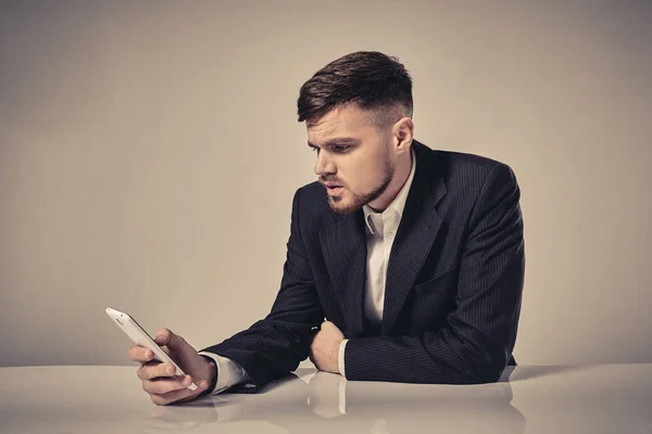 Joven guapo hablando en el teléfono móvil mientras está sentado en su lugar de trabajo en la oficina —  Fotos de Stock