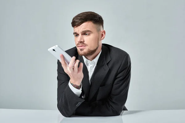 Joven guapo hablando en el teléfono móvil mientras está sentado en su lugar de trabajo en la oficina —  Fotos de Stock
