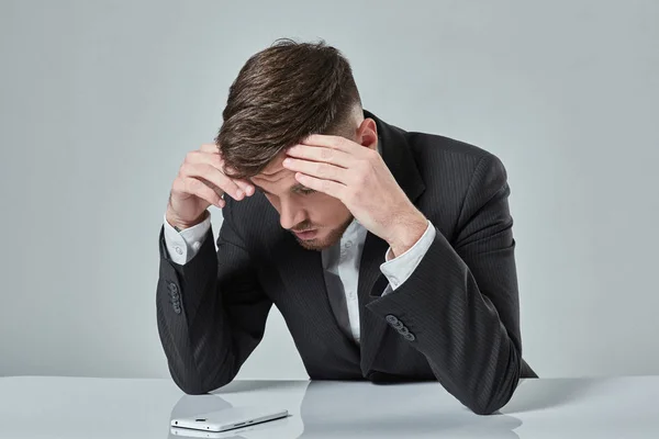 Porträt eines attraktiven jungen kaukasischen Mannes, der Mobiltelefone benutzt, während er am Bürotisch sitzt. — Stockfoto