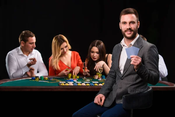 Pokerspelare i casino med kort och marker på svart bakgrund — Stockfoto