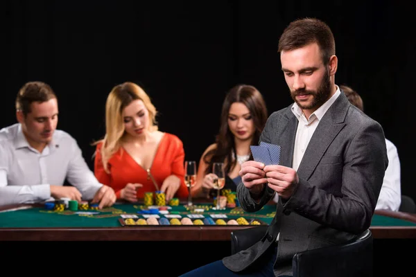 Jugadores de poker en casino con cartas y fichas sobre fondo negro — Foto de Stock