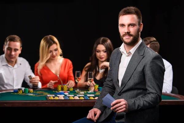 Jugadores de poker en casino con cartas y fichas sobre fondo negro —  Fotos de Stock