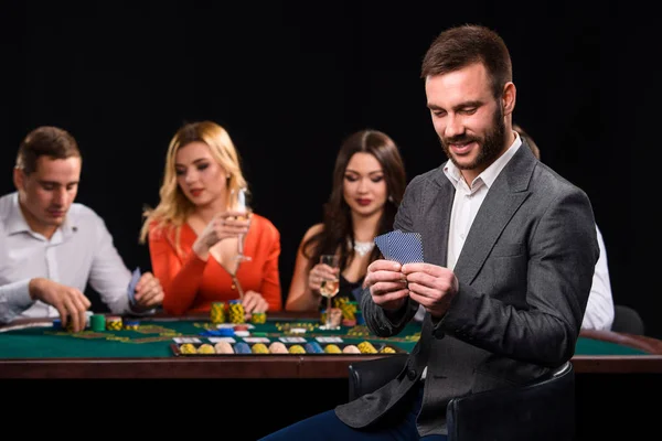 Poker spelers in casino met kaarten en chips op zwarte achtergrond — Stockfoto