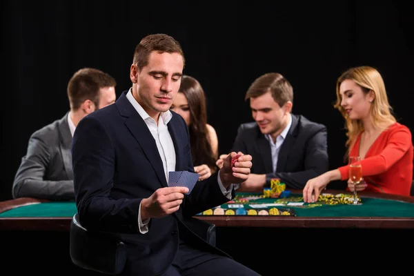 Poker hráči v kasinu s kartami a žetony na černém pozadí — Stock fotografie