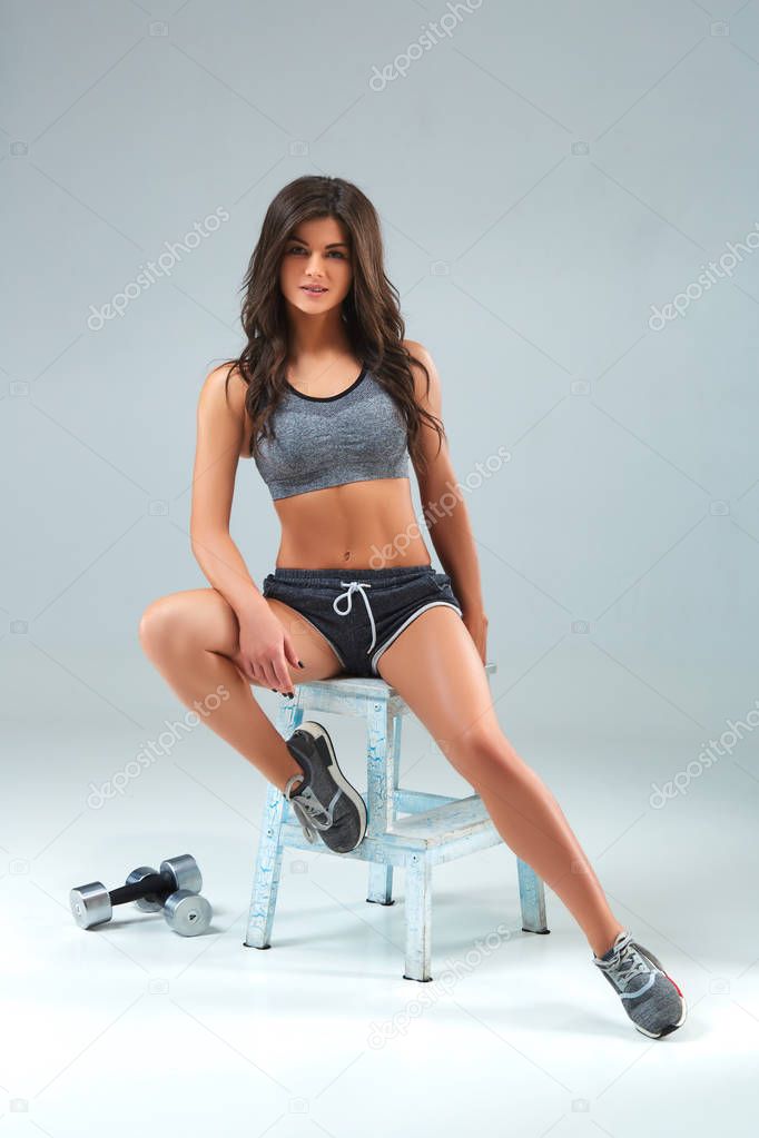 Portrait of young female athlete sitting in a sportswear in the studio