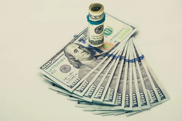 A coiled 100 dollar bill which rests on another angled 100 dollar bill isolated on white background