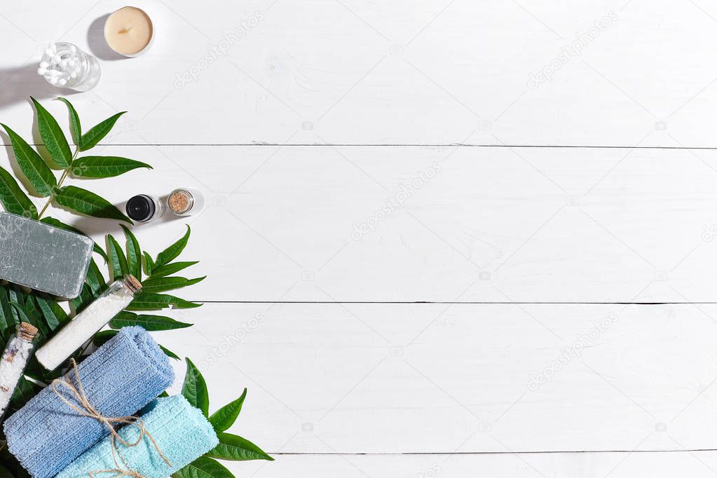 Spa set with towels and soap on white wooden background top view