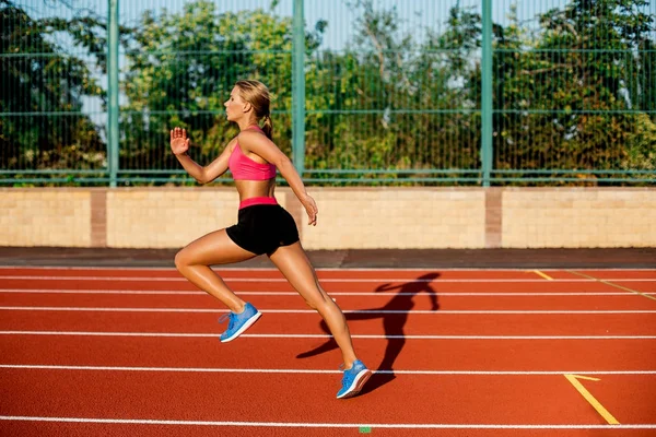 Piękny widok z boku młoda kobieta ćwiczenia, jogging i uruchomiona na torze lekkoatletycznego na stadion — Zdjęcie stockowe