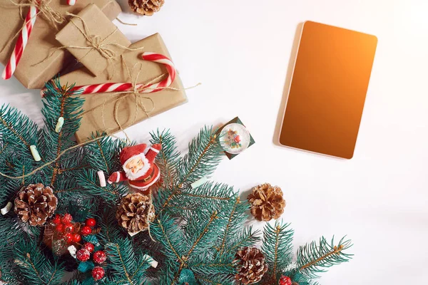 Jul online shopping bakgrund. Tablet PC-skärmen med kopia utrymme, spruce grenar, gåvor på vit bakgrund. Solen flare — Stockfoto