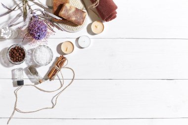 Beyaz ahşap zemin üzerinde kuru çiçek spa set deniz tuzu, uçucu yağ, sabun ve havlu ile süslenmiş