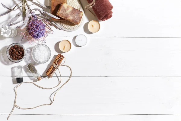 Beyaz ahşap zemin üzerinde kuru çiçek spa set deniz tuzu, uçucu yağ, sabun ve havlu ile süslenmiş