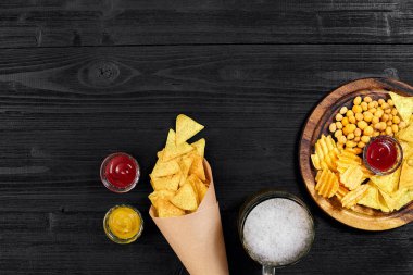 Lager bira ve siyah ahşap masa snacks. Kuruyemiş, cips. Üstten Görünüm ile boşaltmak