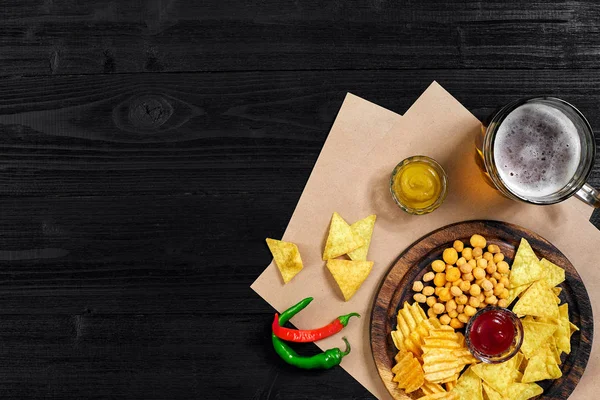 Lager bira ve siyah ahşap masa snacks. Kuruyemiş, cips. Üstten Görünüm ile boşaltmak