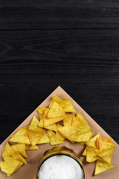 Siyah ahşap zemin üzerine tortilla cips ve bira cam Üstten Görünüm