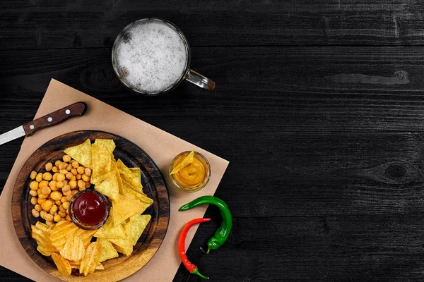 Lager bira ve siyah ahşap masa snacks. Kuruyemiş, cips. Üstten Görünüm ile boşaltmak