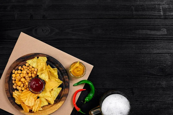 Lager bira ve siyah ahşap masa snacks. Kuruyemiş, cips. Üstten Görünüm ile boşaltmak