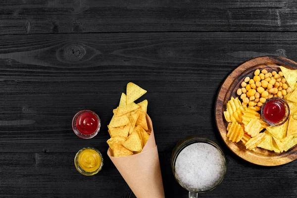 Lager bira ve siyah ahşap masa snacks. Kuruyemiş, cips. Üstten Görünüm ile boşaltmak