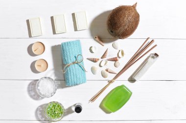 Beyaz ahşap zemin üzerinde deniz kabuklarını spa set deniz tuzu, uçucu yağ, sabun ve havlu ile süslenmiş