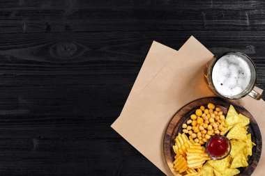 Lager bira ve siyah ahşap masa snacks. Kuruyemiş, cips. Üstten Görünüm ile boşaltmak