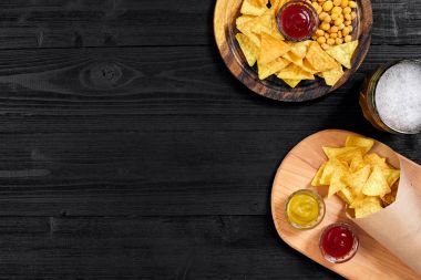 Lager bira ve siyah ahşap masa snacks. Kuruyemiş, cips. Üstten Görünüm ile boşaltmak
