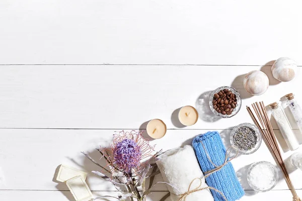 Spa set with sea salt, essential oil, soap and towel decorated with dry flower on white wooden background — Stock Photo, Image