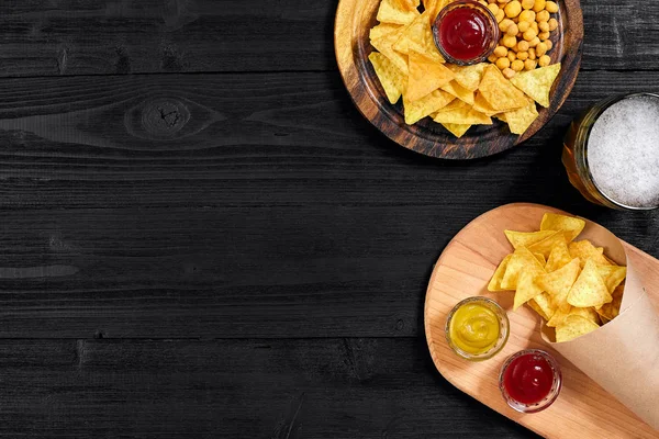Lager bira ve siyah ahşap masa snacks. Kuruyemiş, cips. Üstten Görünüm ile boşaltmak