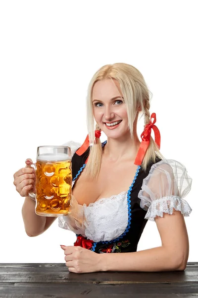 Dirndl beyaz zemin üzerine bira ile masada oturan genç Bavyera kadın — Stok fotoğraf