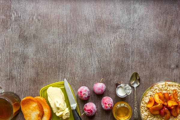 Овсянка со сливами, тосты с маслом и медом на деревянном столе. Концепция здорового завтрака — стоковое фото